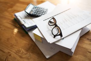 stack of QBI documents with glasses and a calculator