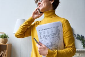 woman talking on the phone with tax documents in arm