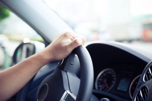 hand on steering wheel calculating mileage rates