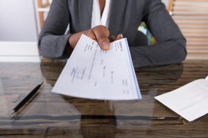 woman handing out a payroll check to prevent payroll fraud schemes